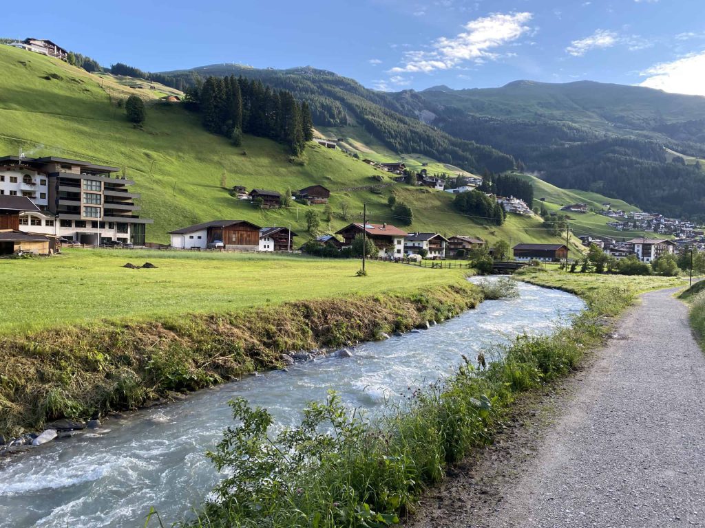 Ein Angler mit Rute am idyllischen See in Österreich, umgeben von Bergen und Wald